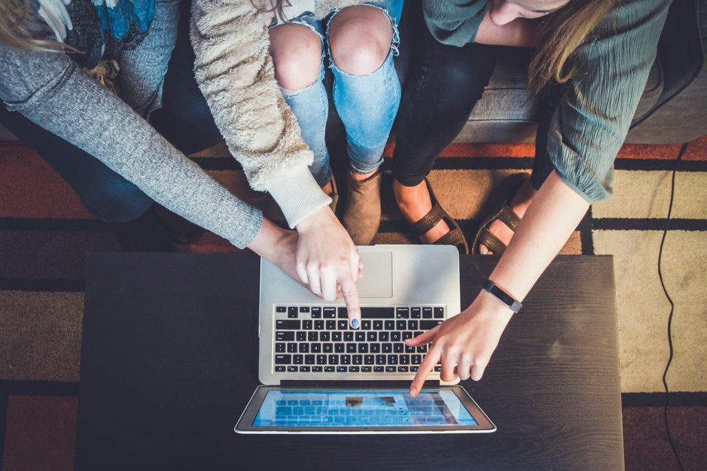 Group of friends gathered around computer to look at website representing high traffic