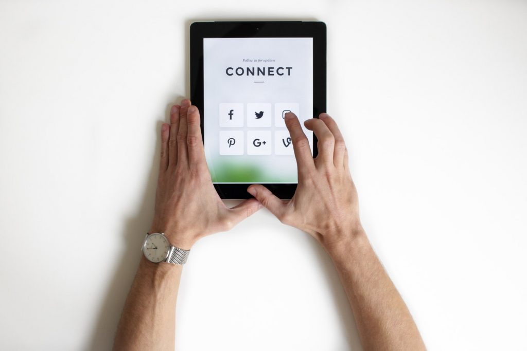 Man holding tablet showing social media platforms