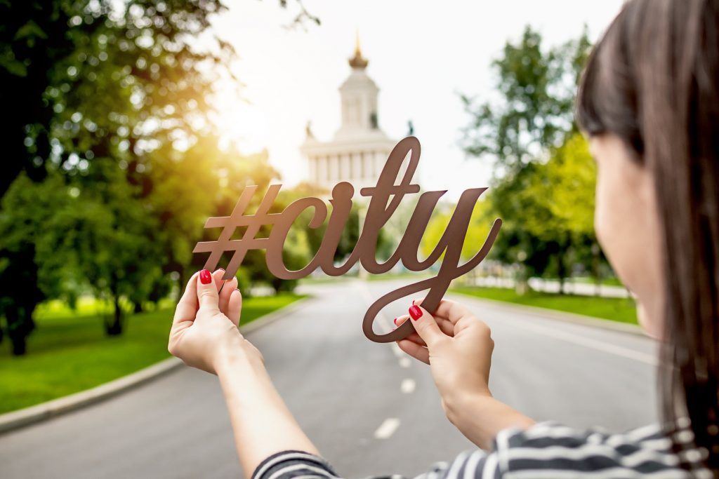 Woman holding high traffic hashtags that says 'city'